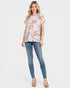 Woman wearing a floral top and blue jeans on a white background