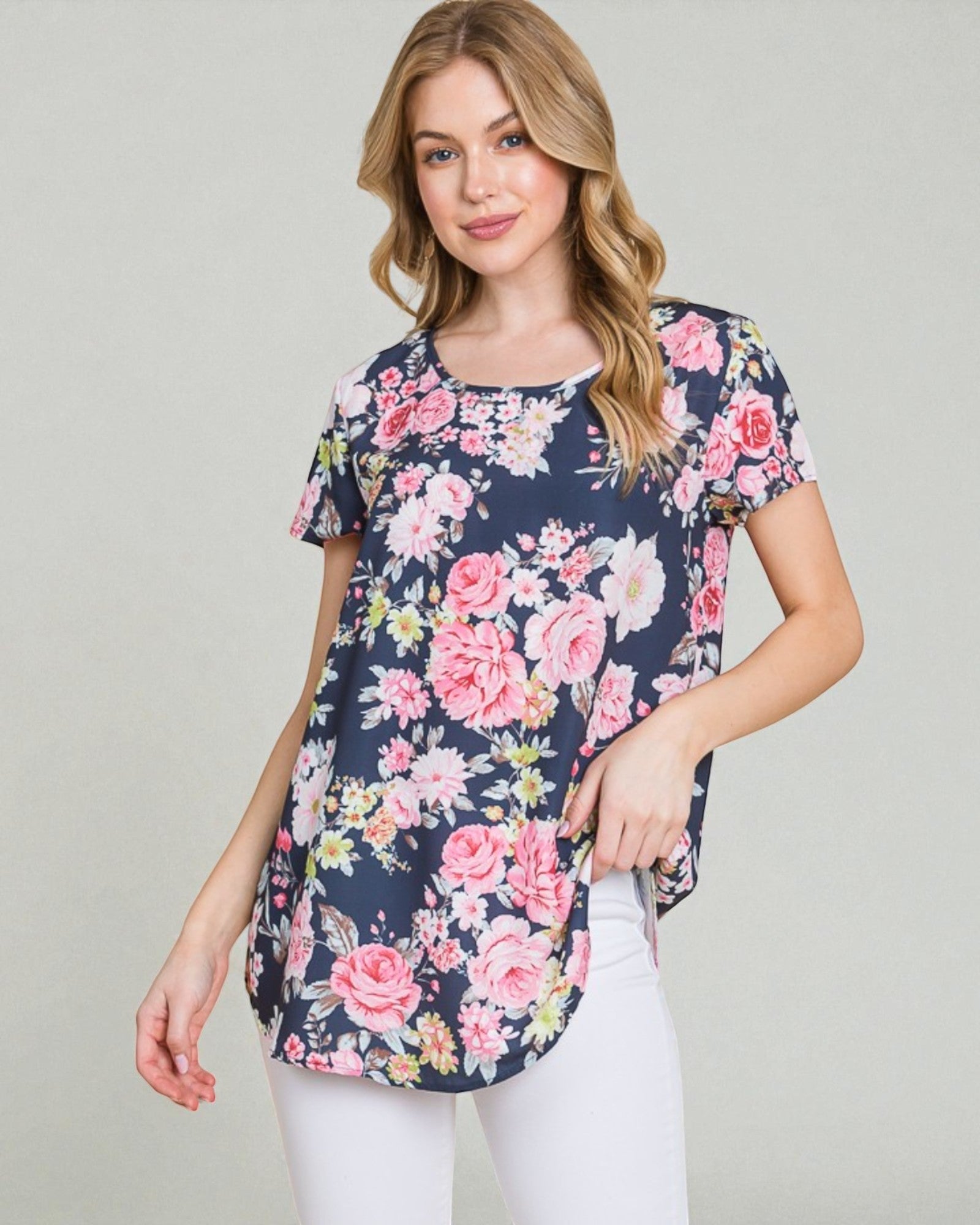 Woman wearing a navy floral tunic with pink and white flowers on a plain background