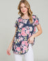Woman wearing a navy floral tunic with pink and white flowers on a plain background