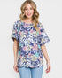 Woman wearing a floral patterned shirt on a plain background