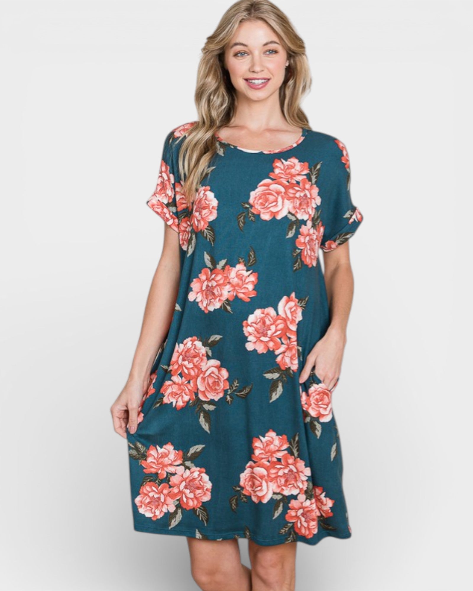 Woman wearing a teal dress with pink floral pattern on a white background