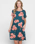 Woman wearing a teal dress with pink floral pattern on a white background