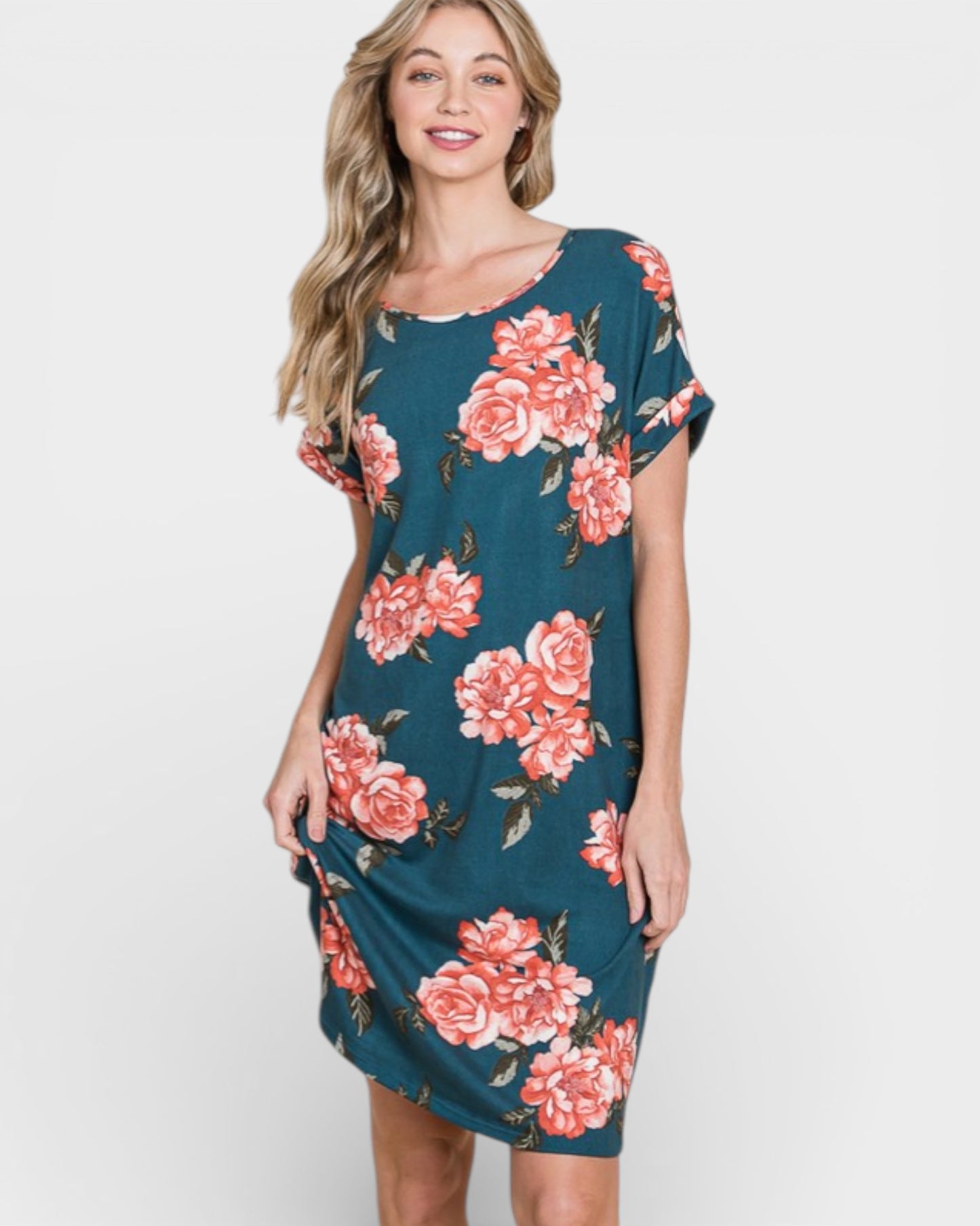 Woman wearing a teal dress with pink floral pattern on a white background