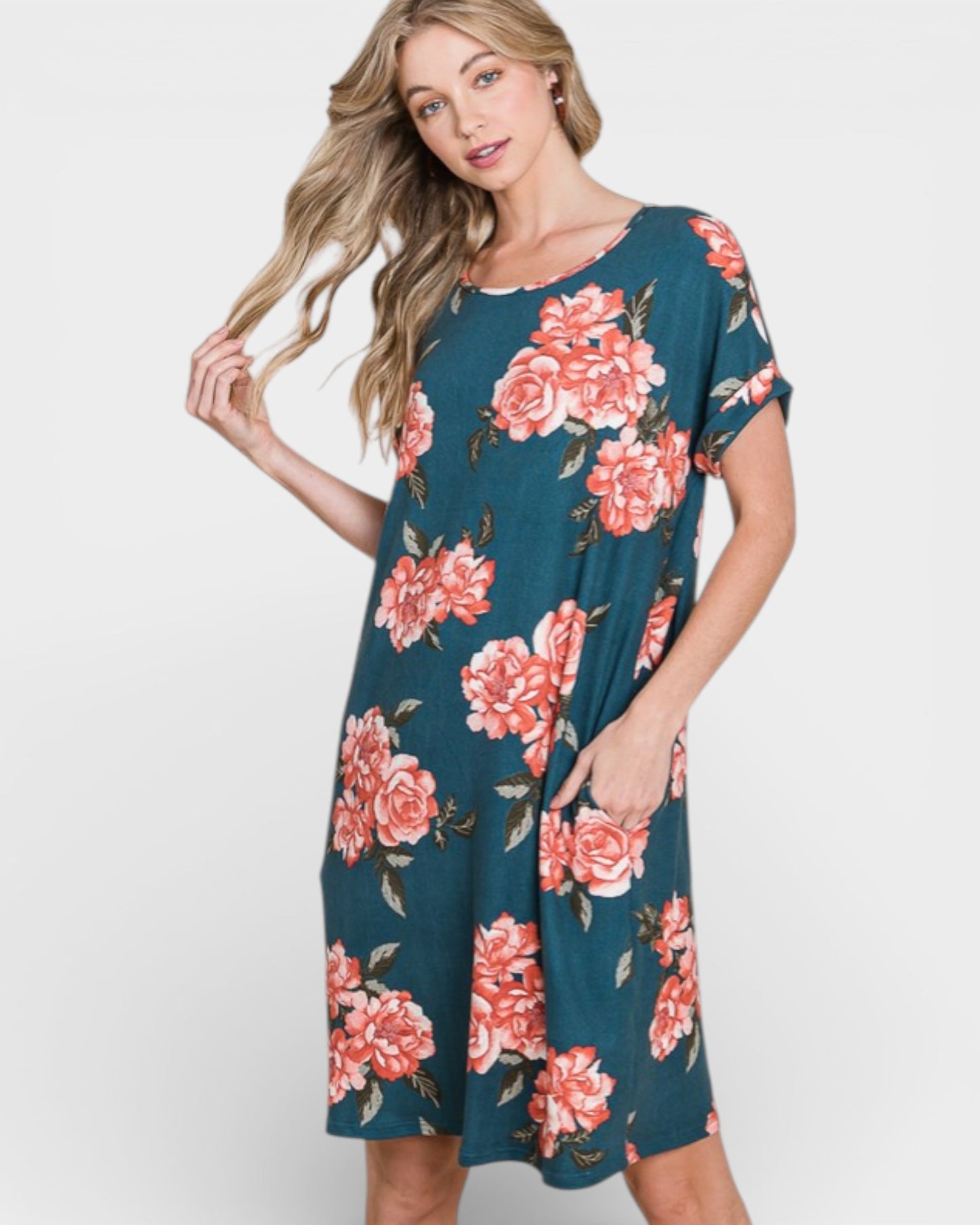 Woman wearing a teal dress with pink floral pattern on a white background