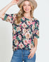 Woman wearing a floral blouse and jeans with a neutral background