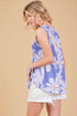 Woman wearing a sleeveless floral top with a beige background