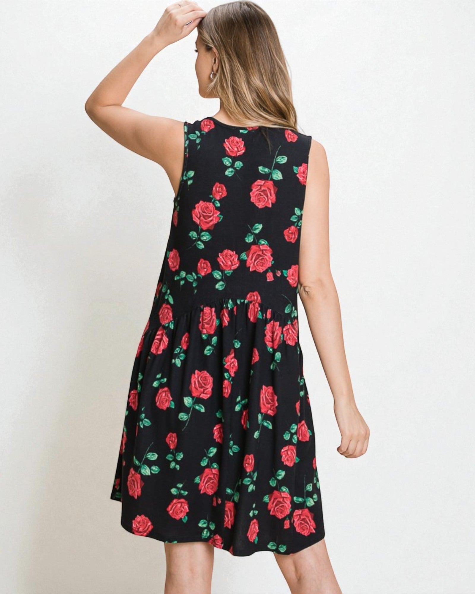Woman wearing a black sleeveless dress with red rose pattern on a white background