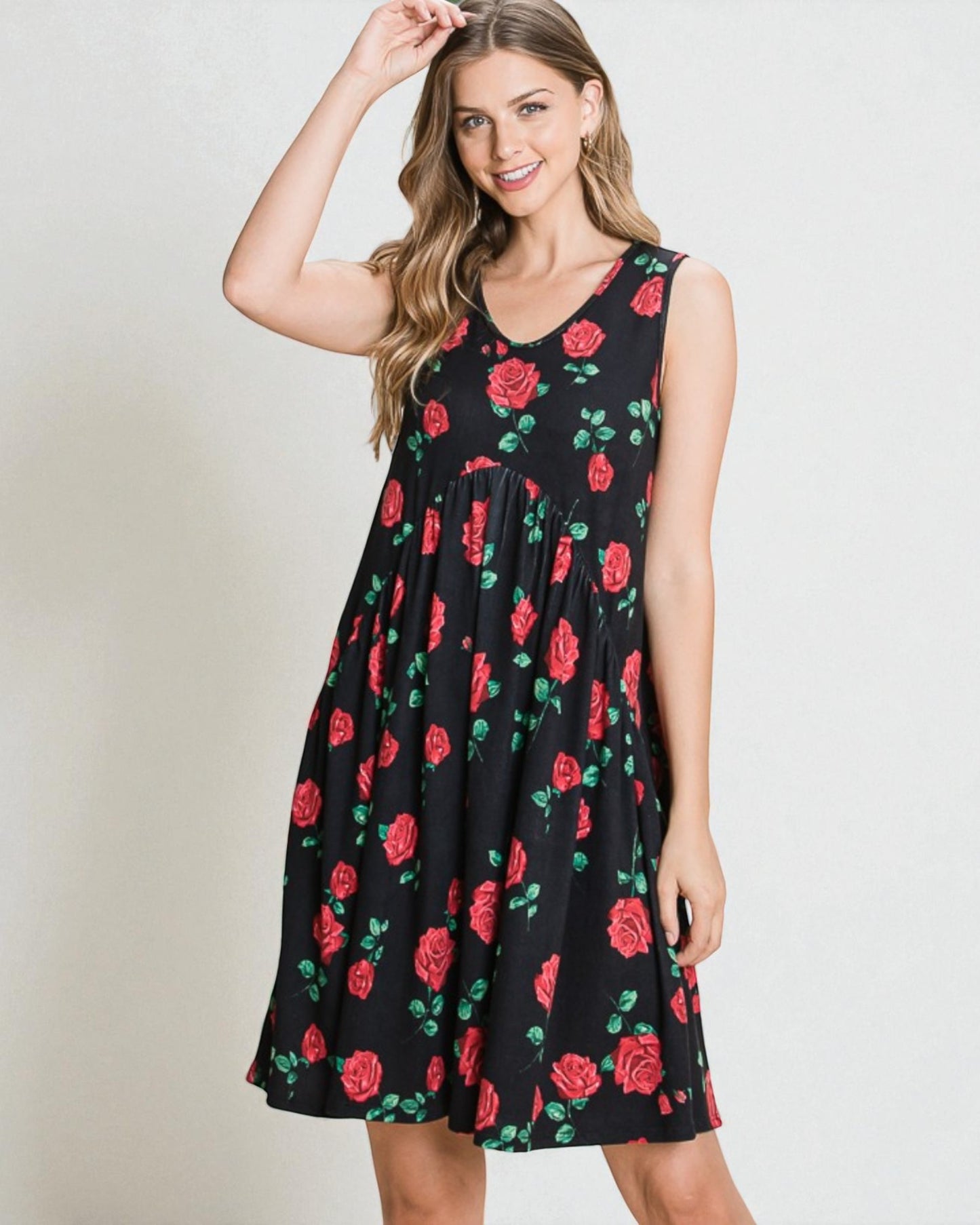 Woman wearing a black sleeveless dress with red rose pattern on a plain background
