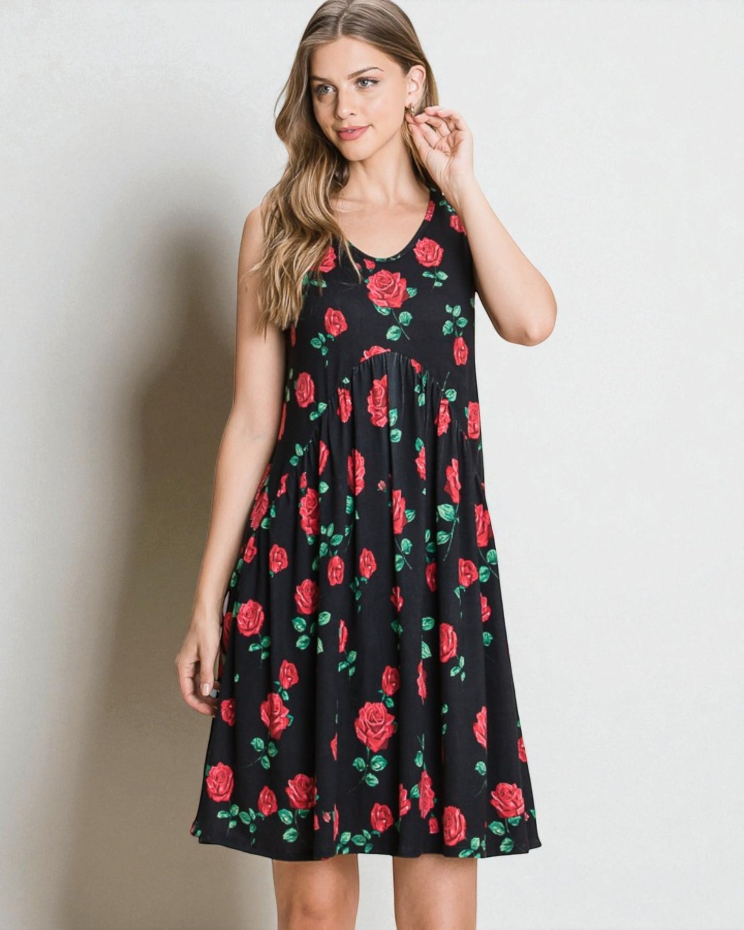 Woman wearing a black dress with red rose pattern against a plain background