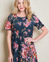 Woman wearing a navy floral dress against a plain background