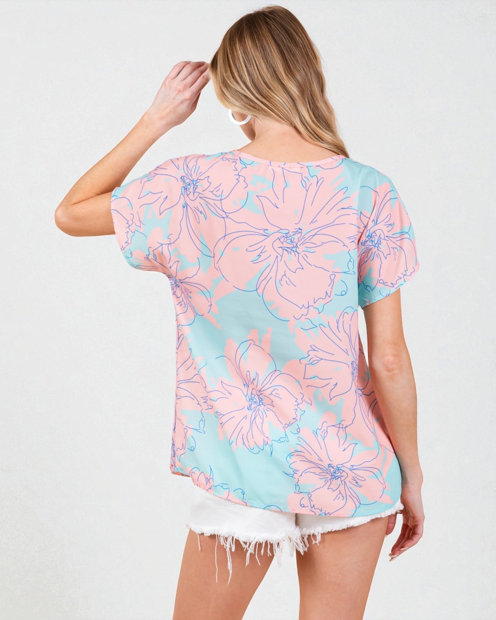 Woman wearing a pastel floral patterned top on a white background