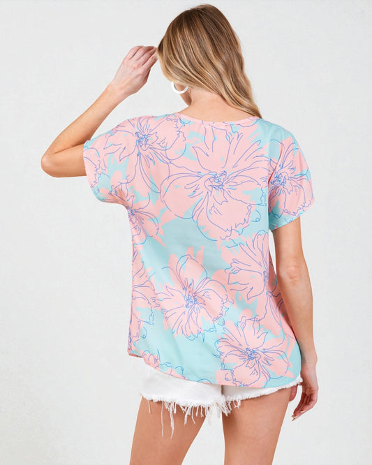 Woman wearing a pastel floral patterned top on a white background