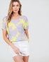 Woman wearing a colorful floral top and white shorts on a plain background