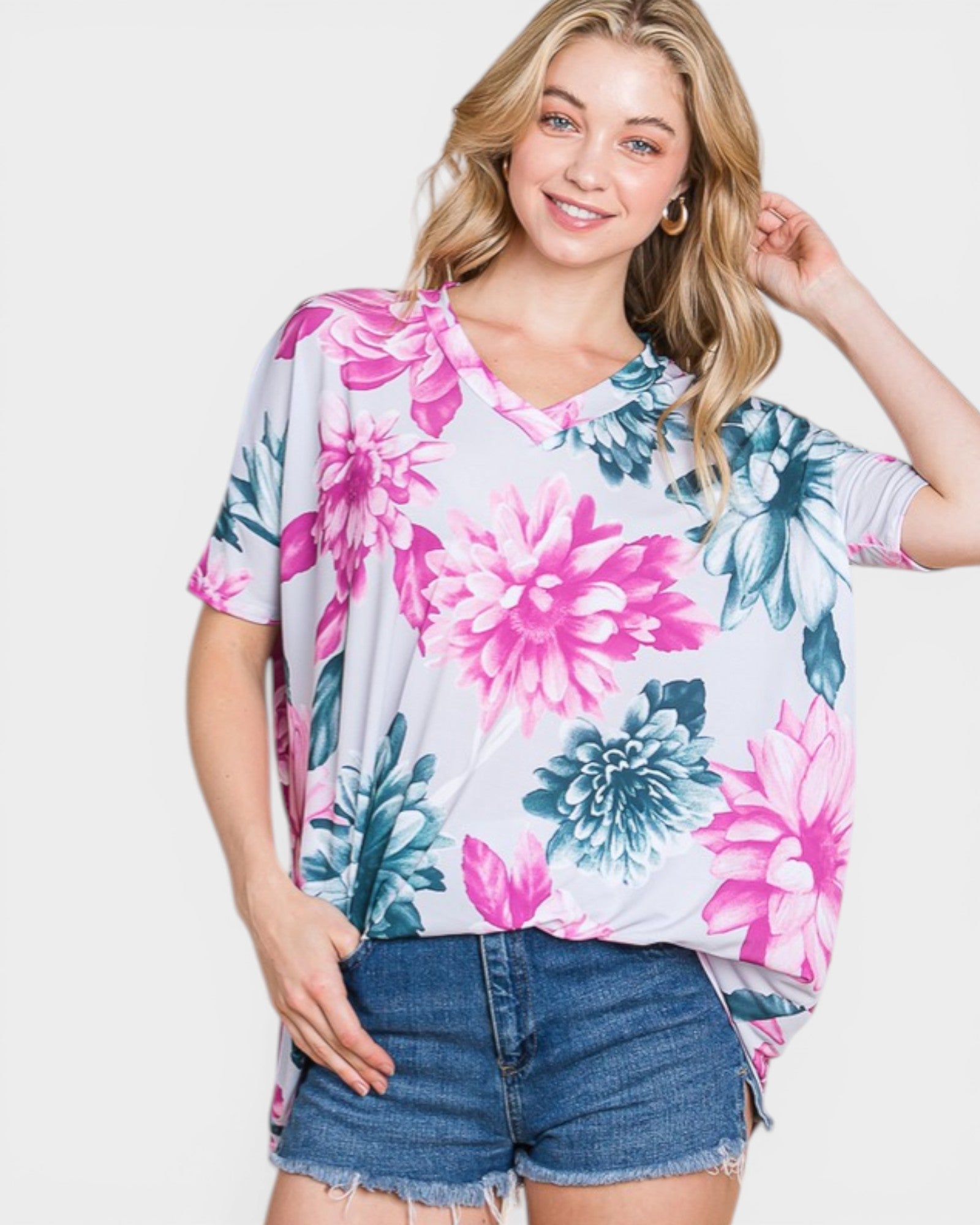 Woman wearing a floral oversized shirt and denim shorts on a white background