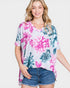 Woman wearing a floral top and denim shorts on a plain background