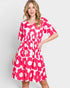 Woman wearing a pink floral dress on a light gray background