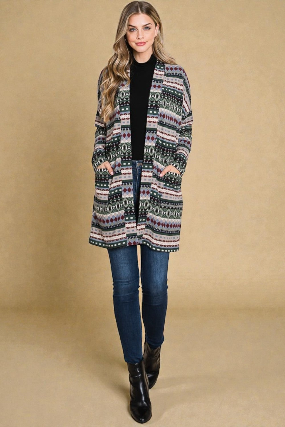 Woman wearing a patterned coat, black top, blue jeans, and black boots on a beige background