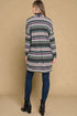 Person wearing a patterned cardigan and blue jeans against a beige background