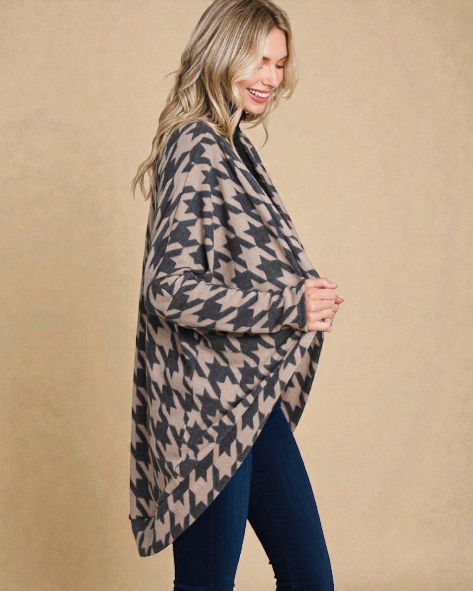 Woman wearing a houndstooth patterned poncho against a beige background
