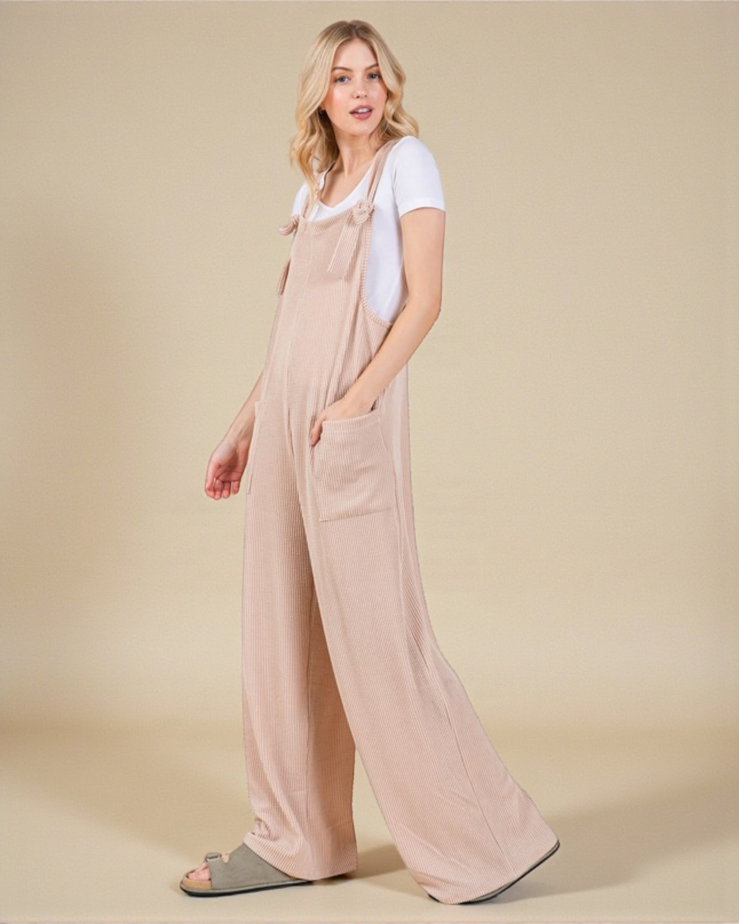 Woman wearing a beige overalls with a plain background