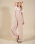 Woman wearing a beige overalls with a plain background