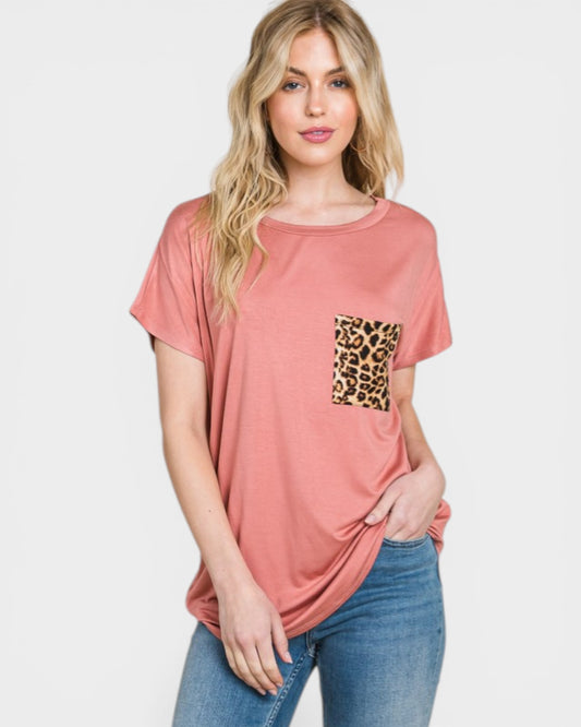 Woman wearing a pink t-shirt with a leopard print pocket on a white background