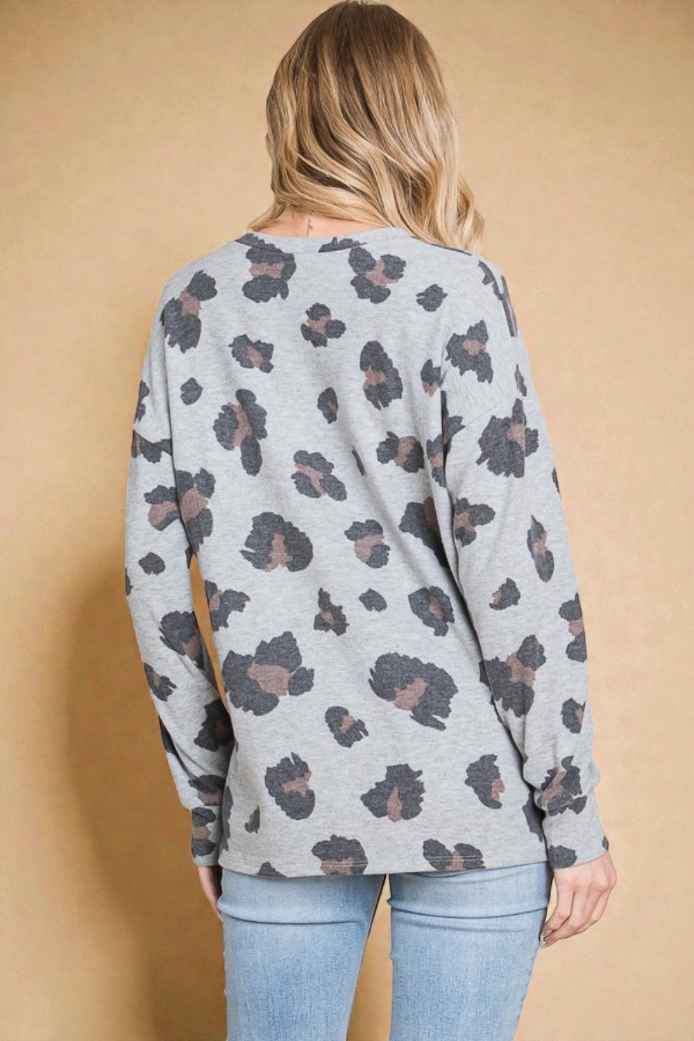 Person wearing a gray sweater with a floral pattern against a beige background