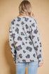 Person wearing a gray sweater with a floral pattern against a beige background