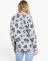 A woman shown from the back wearing a light gray long-sleeve top with a dark gray and brown leopard print, paired with light blue jeans, against a plain white background.