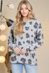 Woman wearing a gray sweater with leopard print pattern against a neutral background