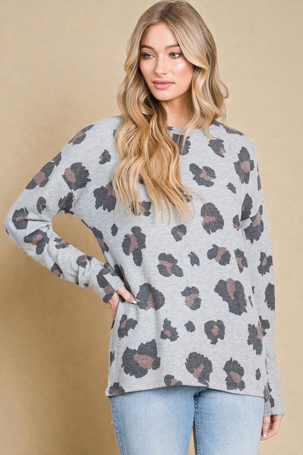 Woman wearing a gray sweater with a leopard print pattern against a beige background