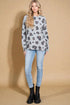 Woman wearing a patterned sweater and light blue jeans against a beige background