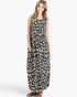A woman modeling a sleeveless black maxi dress with a white abstract animal print pattern, featuring side pockets and a relaxed fit, set against a plain light gray background.
