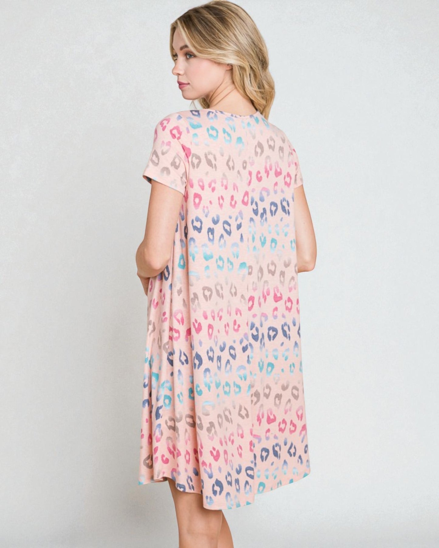 Woman wearing a pastel leopard print dress against a white background