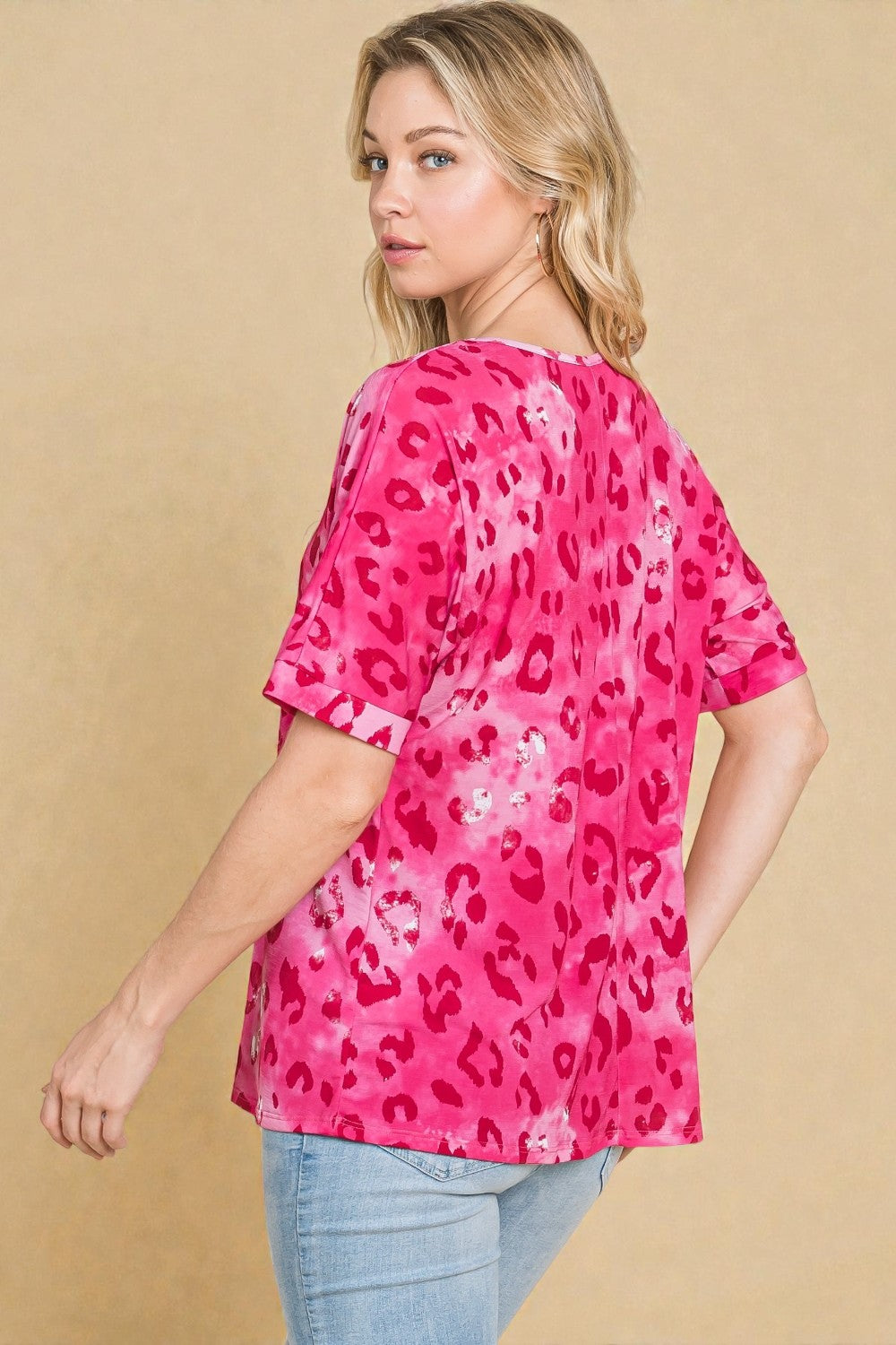 Woman wearing a pink leopard print top against a beige background