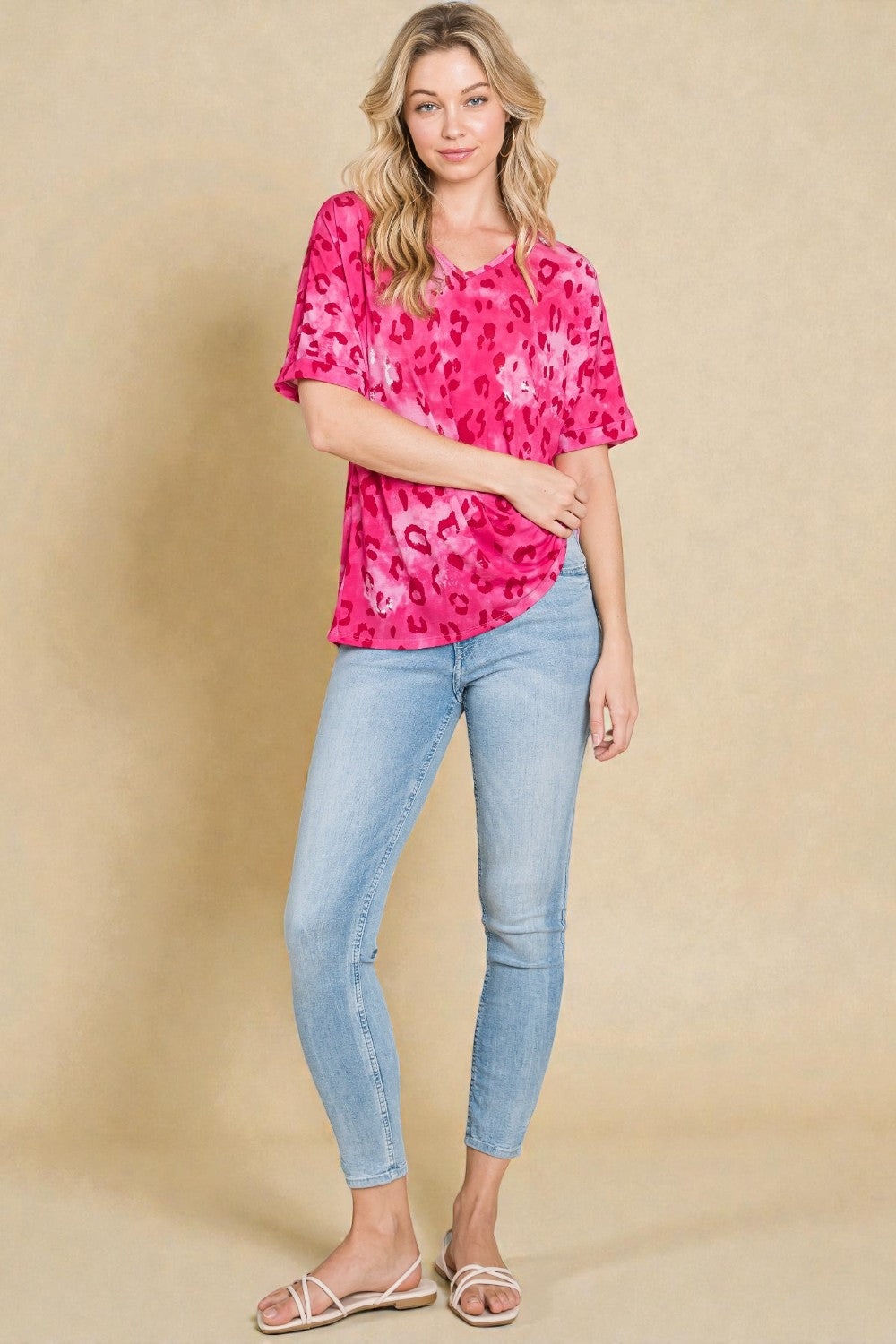 Woman wearing a pink floral top and blue jeans against a beige background