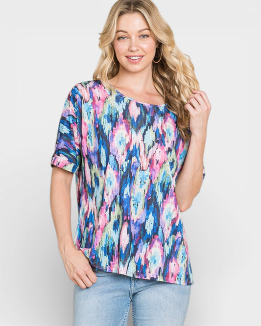 Woman wearing a colorful floral blouse against a plain background