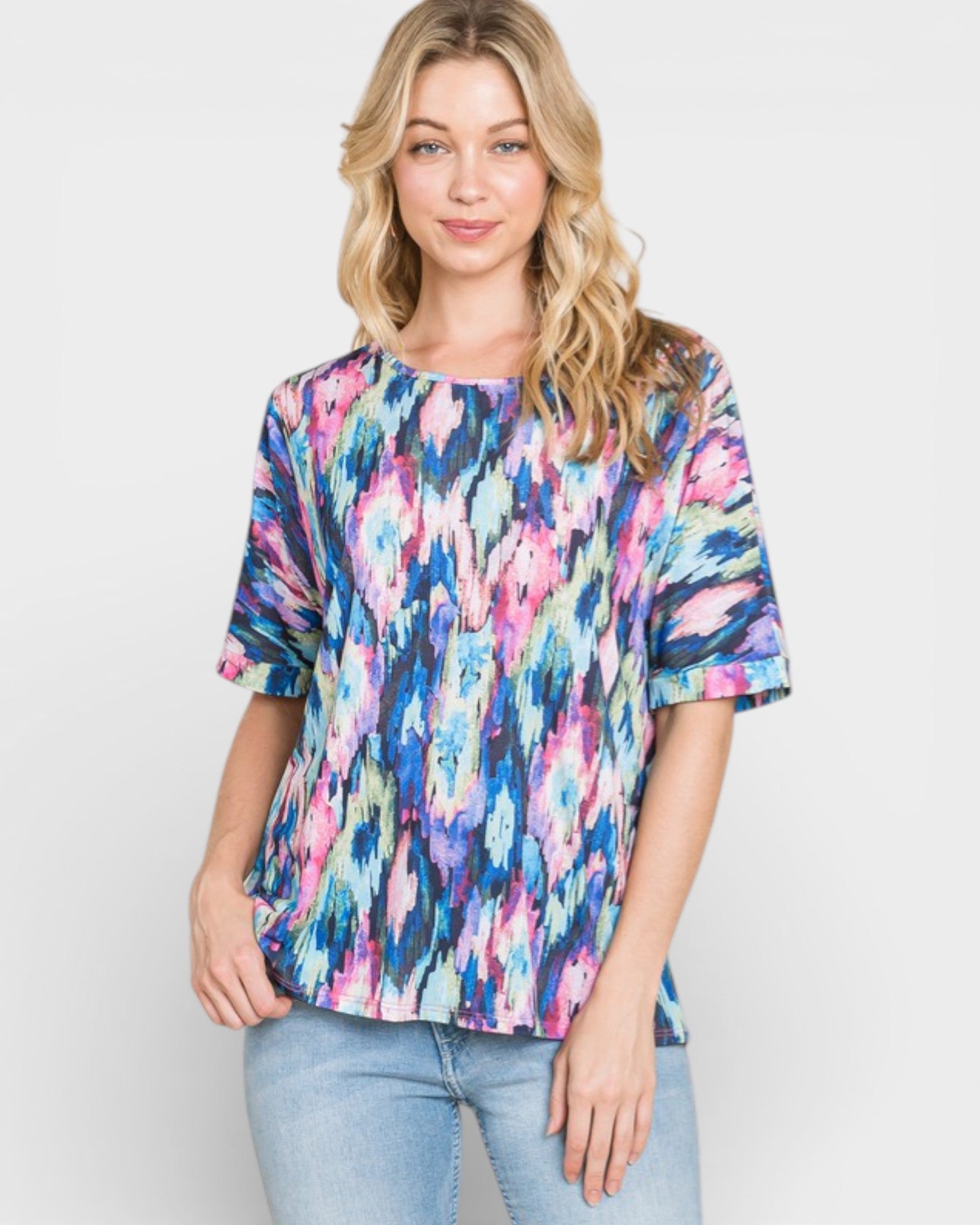 Woman wearing a colorful abstract patterned top against a plain background
