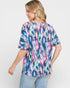 Woman wearing a colorful abstract patterned top on a white background