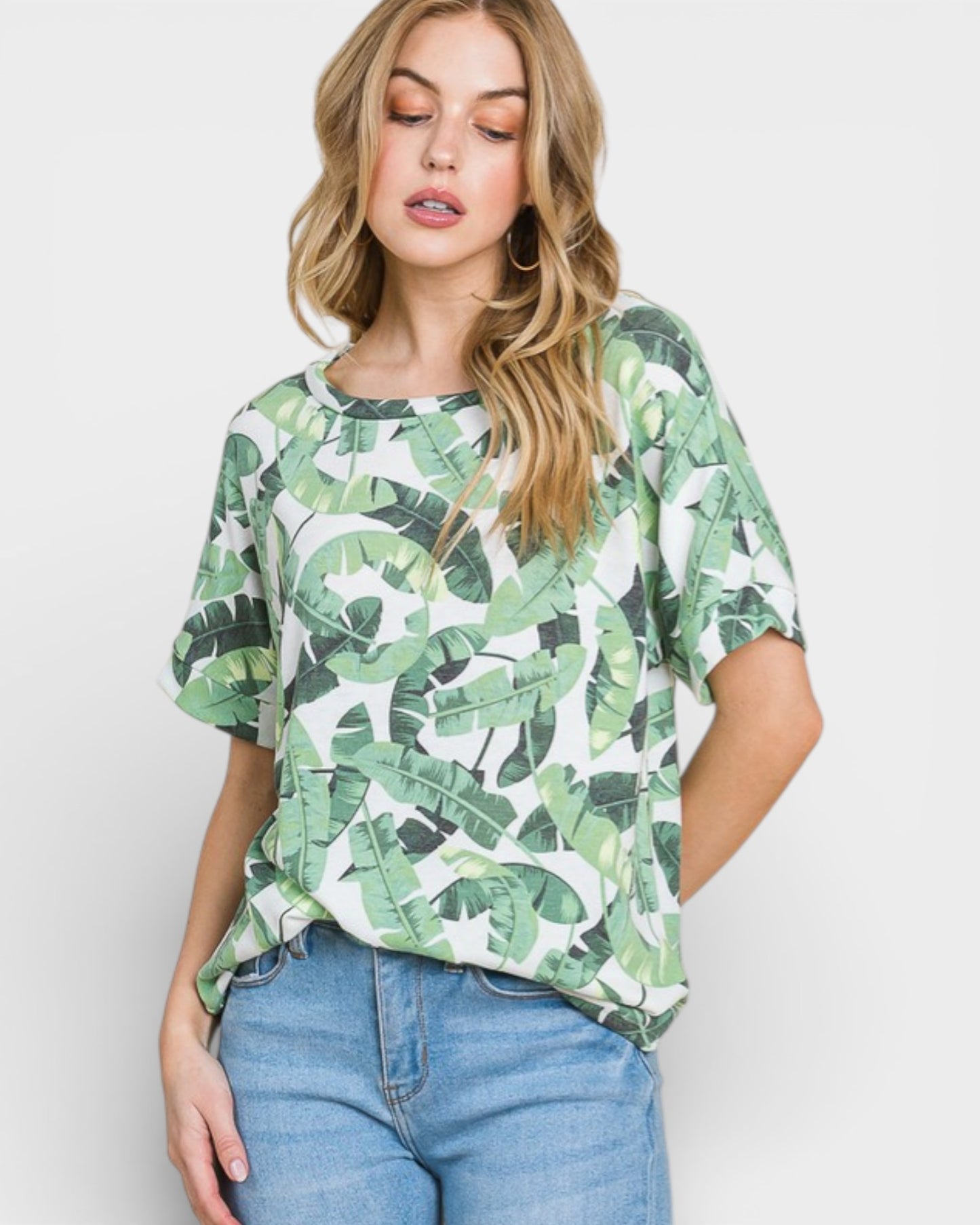 Woman wearing a green leaf patterned shirt and blue jeans on a white background