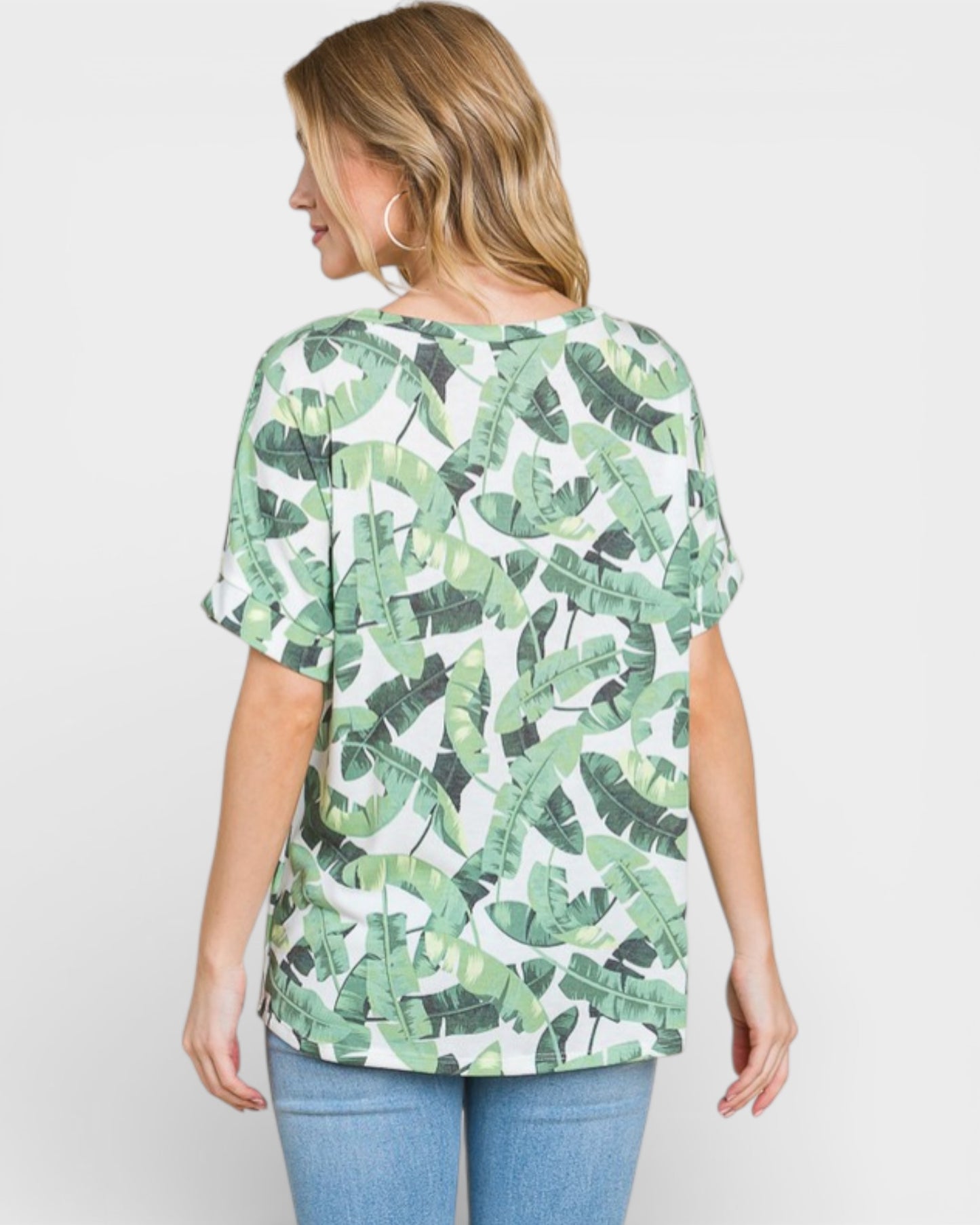 Woman wearing a green leaf patterned top on a white background
