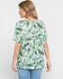 Woman wearing a green leaf patterned top on a white background