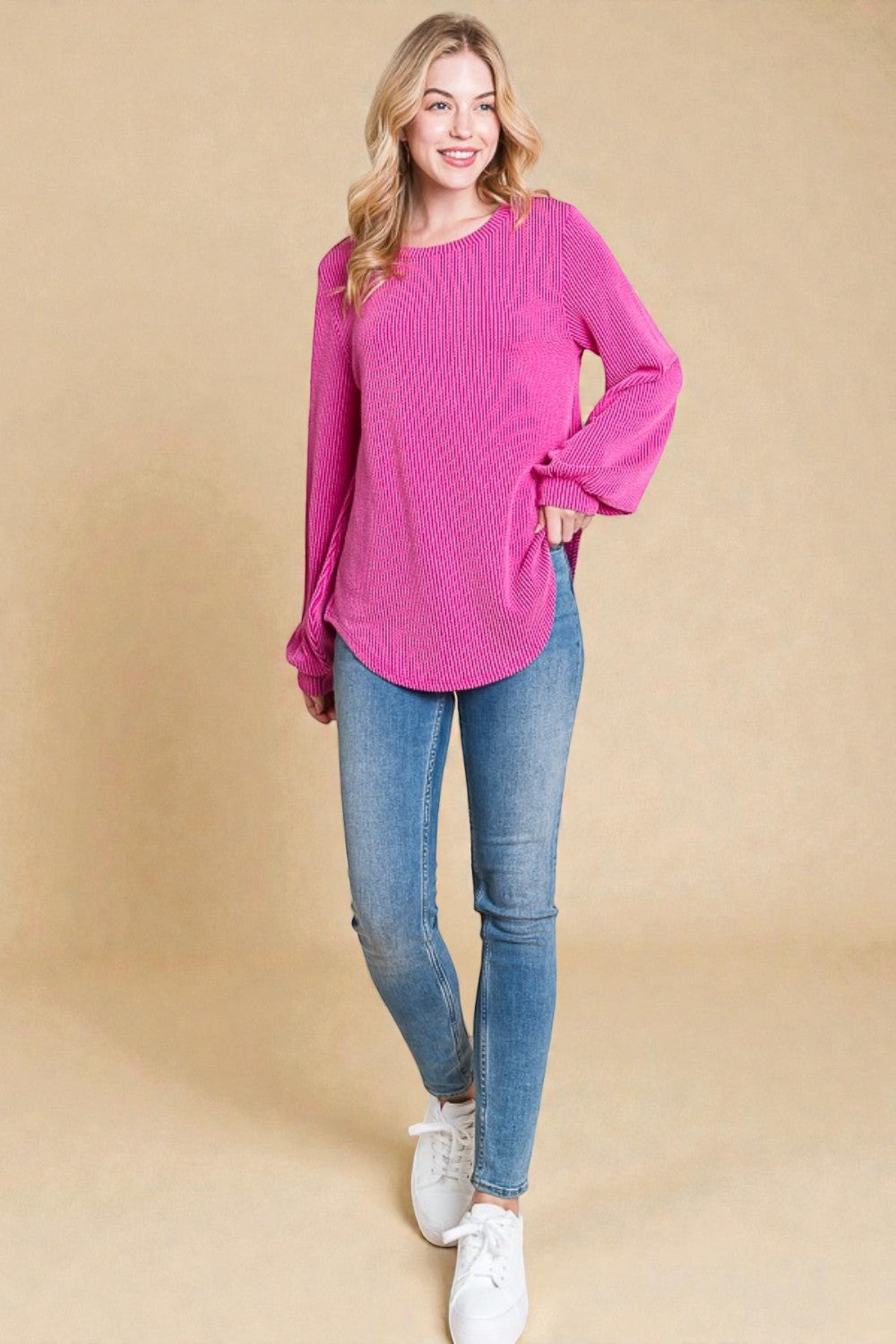 Woman wearing a pink sweater and blue jeans on a beige background