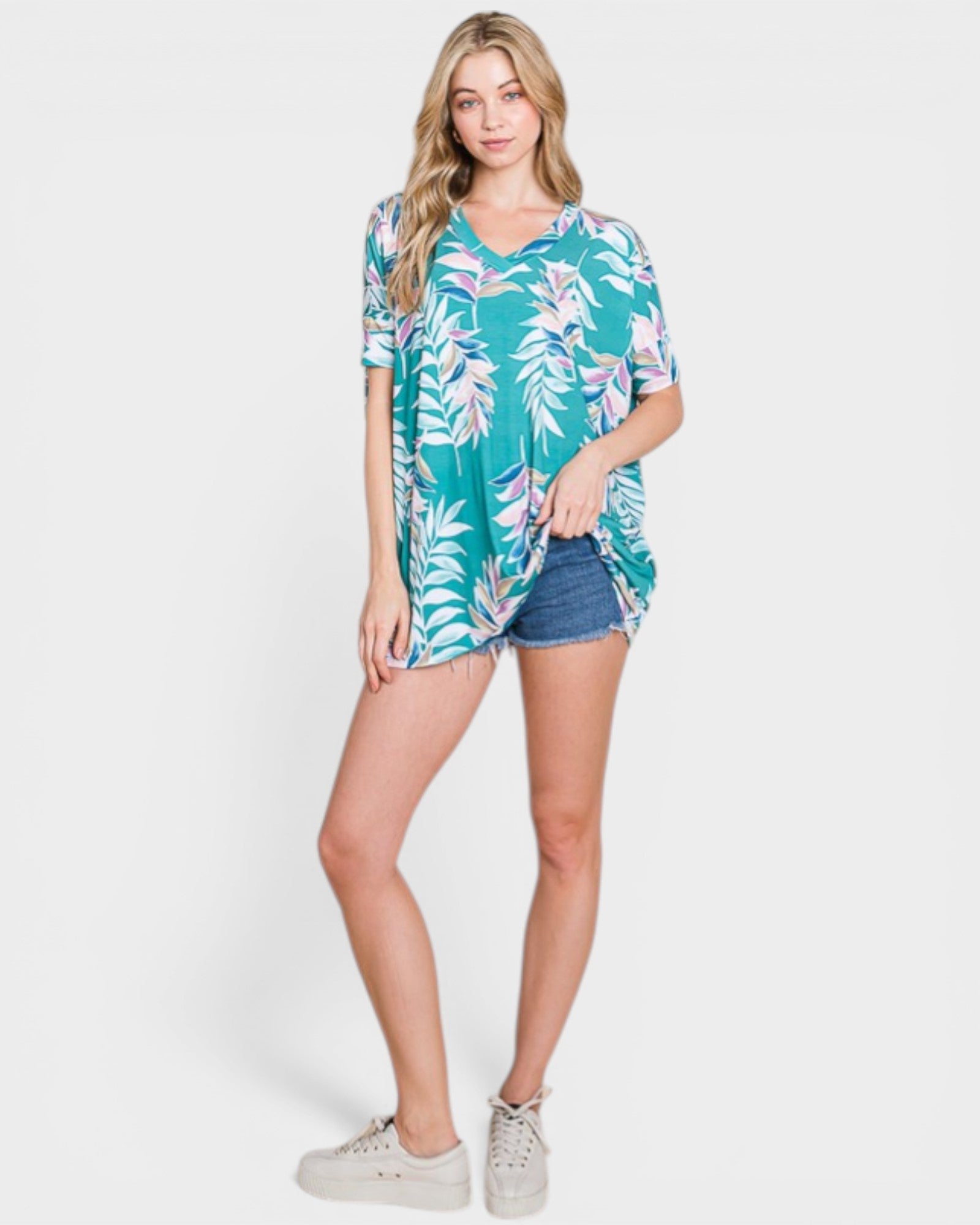 Woman wearing a tropical print shirt and denim shorts on a white background