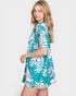 Woman wearing a teal floral dress on a white background