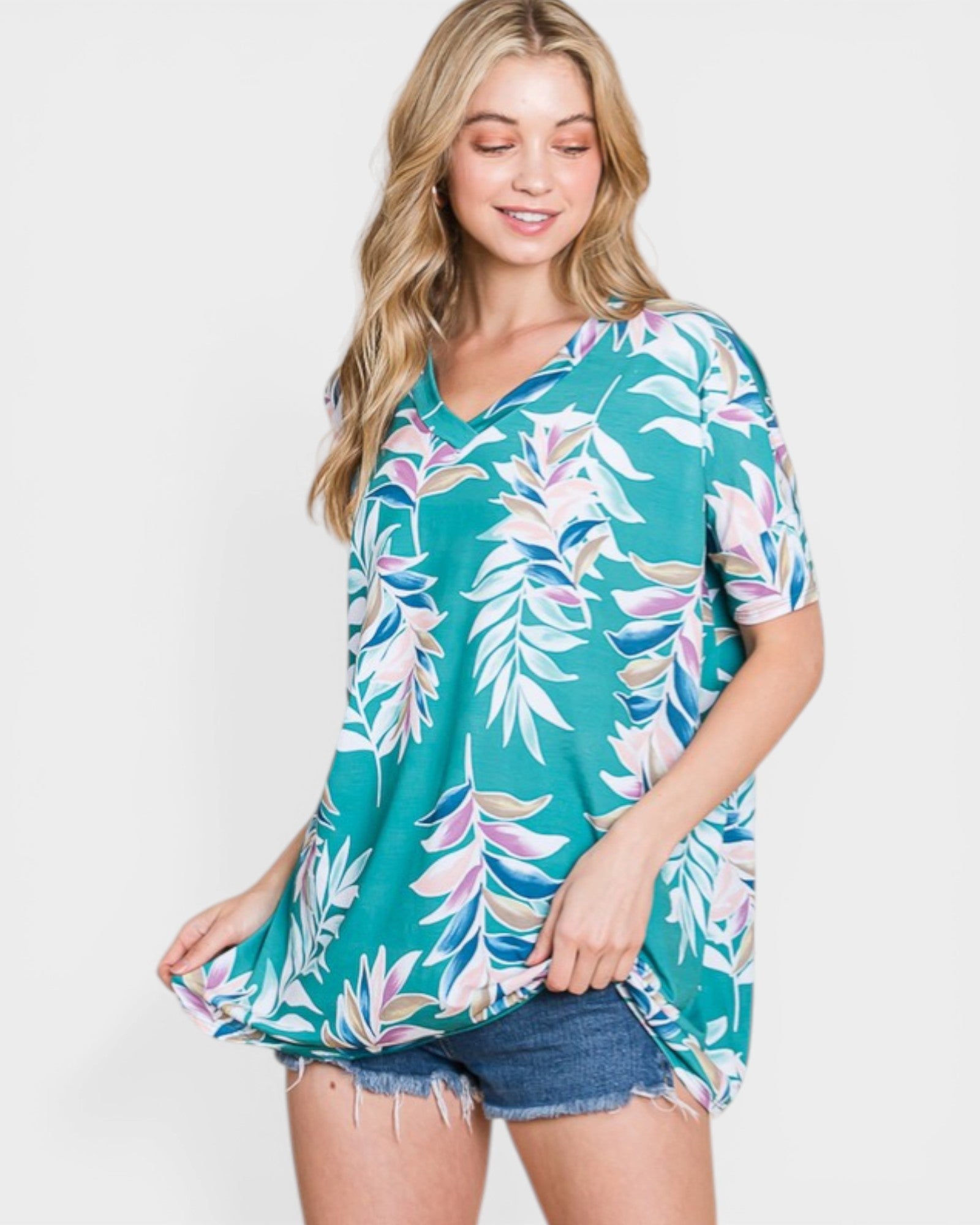 Woman wearing a teal floral print top on a white background