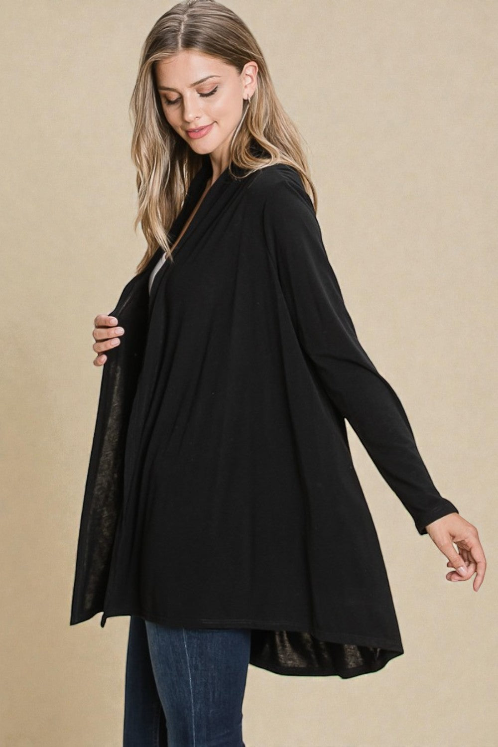 Woman wearing a black cardigan over a black top on a beige background