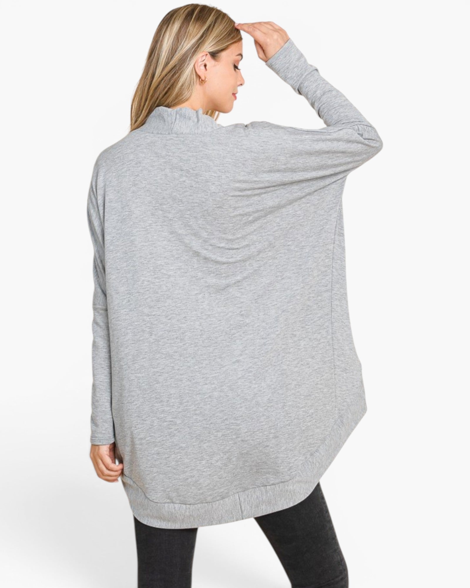 A woman shown from the back wearing a light gray heathered long-sleeve tunic top with a ruffled high neck and a draped, open-front silhouette, paired with black pants against a plain white studio background.