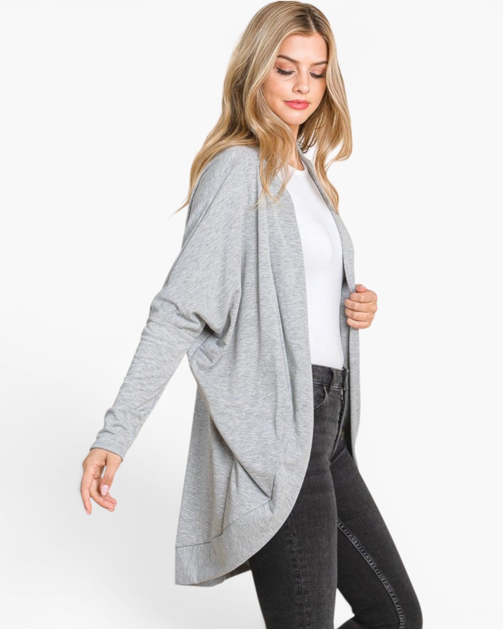 A woman modeling a light gray open-front drape cardigan over a white top and dark gray jeans, photographed against a clean white studio background.