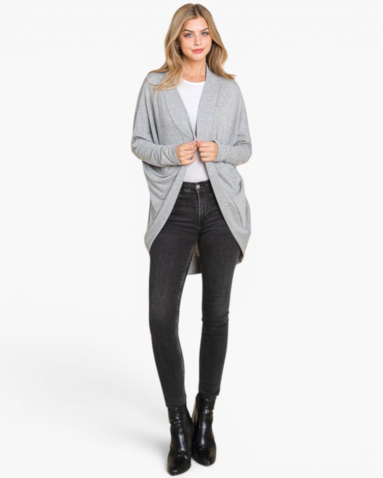 A woman modeling a light gray open-front cardigan over a white top and black skinny jeans, standing against a plain light gray studio background.